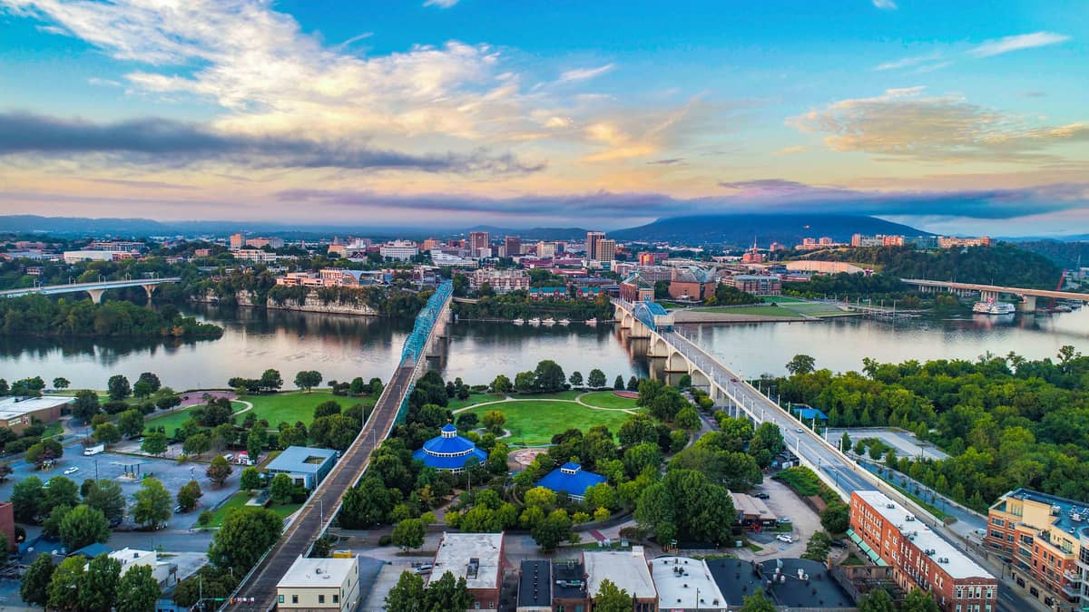 Aerial view of downtown Chattanooga, Tennessee at dusk, with the Tennessee River, the Walnut Street Bridge, and Lookout Mountain